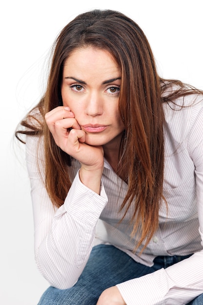 Portrait de jeune femme pensive assise sur une chaise