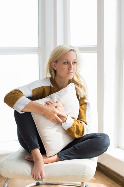 Portrait d&#39;une jeune femme pensive assise à la maison