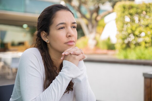 Portrait de jeune femme pensive ou triste assis au café-terrasse