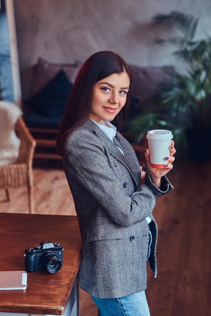 Le portrait d'une jeune femme photographe tient une tasse d'un matin