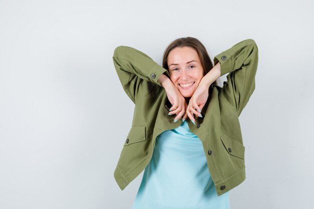 Portrait de jeune femme avec des poignets sur les joues en t-shirt, veste et jolie vue de face