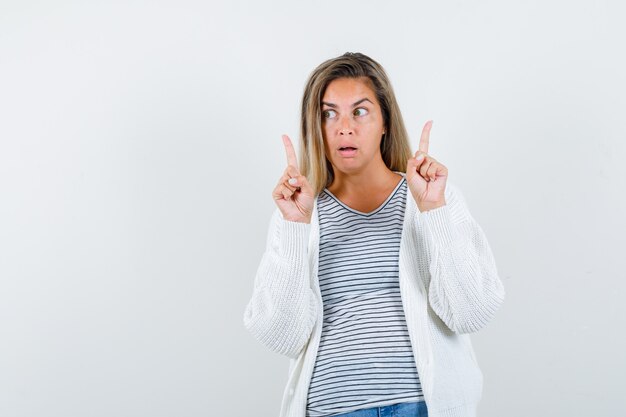 Portrait de jeune femme pointant vers le haut en t-shirt, veste et à la vue de face ciblée