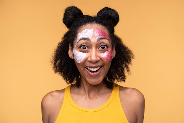 Photo gratuite portrait d'une jeune femme portant une crème hydratante et un masque facial