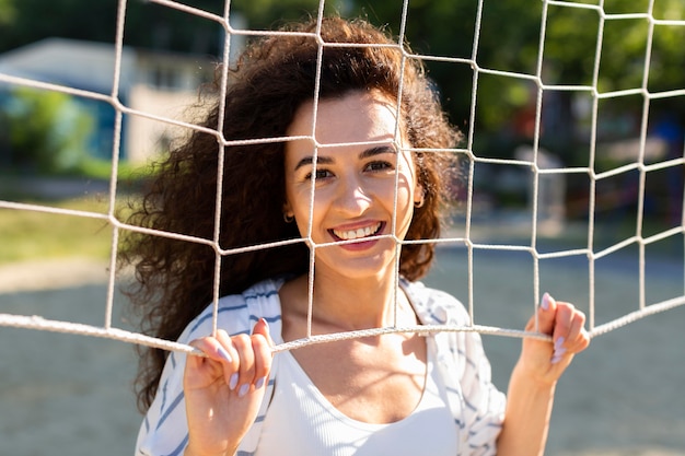 Portrait de jeune femme posant à côté d'un terrain de volley-ball à l'extérieur