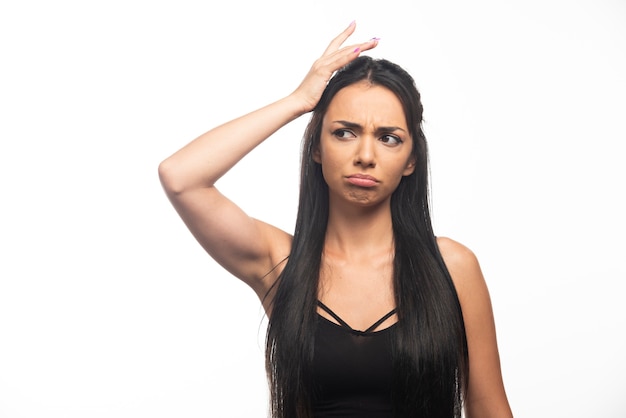 Portrait de jeune femme posant sur mur blanc