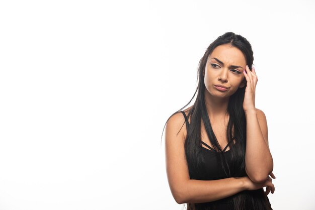 Portrait de jeune femme posant sur mur blanc