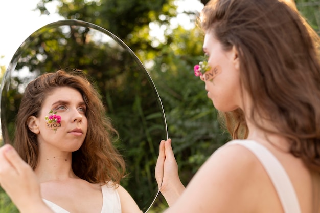 Photo gratuite portrait de jeune femme posant en toute confiance à l'extérieur avec un miroir rond