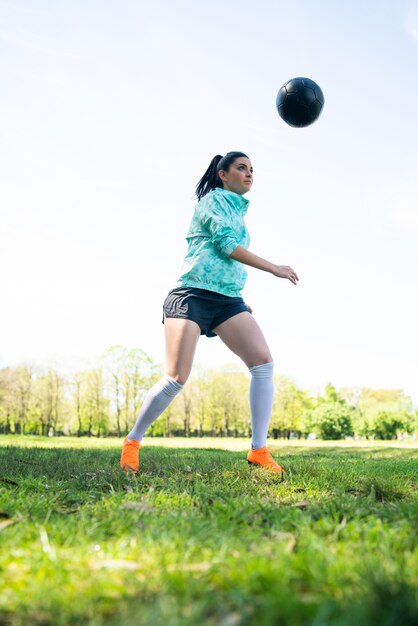Portrait de jeune femme pratiquant le football et faisant des tours avec le ballon de football