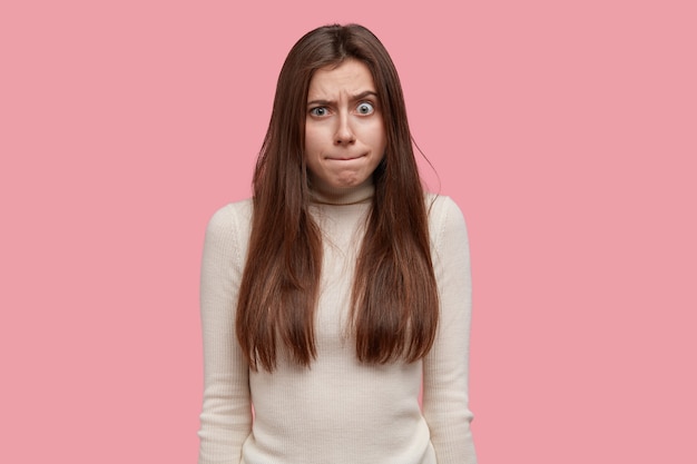 Portrait De Jeune Femme Presse Les Lèvres Et Se Sent Bouleversée Et étonnée, Soulève Les Sourcils, Est Sous Tension Ou Pression