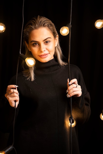 Portrait de jeune femme en pull noir debout et posant