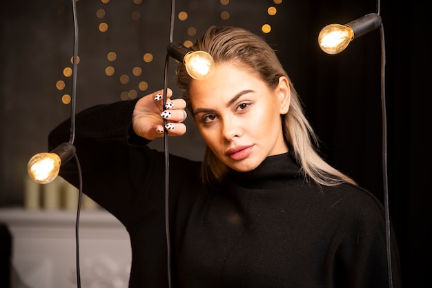 Portrait de jeune femme en pull noir debout et posant.