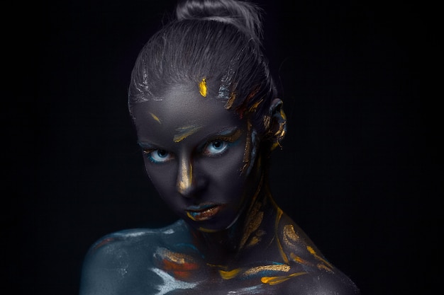 Photo gratuite portrait d'une jeune femme qui pose recouverte de peinture noire