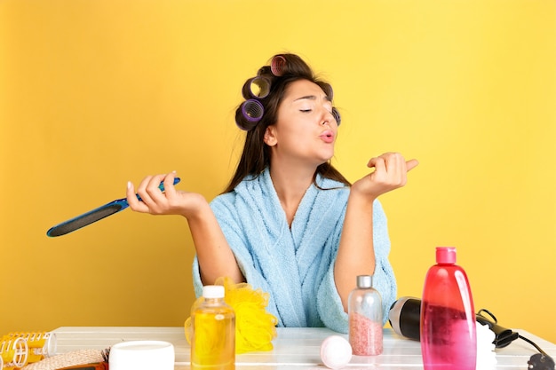 Portrait de jeune femme de race blanche dans sa routine de soins de jour, de peau et de cheveux de beauté. Modèle féminin avec des cosmétiques naturels appliquant de la crème et des huiles pour le maquillage. Soins du corps et du visage, concept de beauté naturelle.