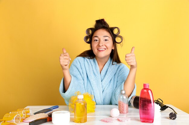 Portrait de jeune femme de race blanche dans sa routine de soins de jour, de peau et de cheveux de beauté. Modèle féminin avec des cosmétiques naturels appliquant de la crème et des huiles pour le maquillage. Soins du corps et du visage, concept de beauté naturelle.