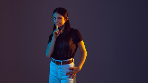 Portrait de jeune femme de race blanche isolé sur fond de studio à la lumière du néon.