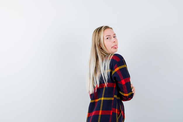 Portrait De Jeune Femme Regardant Par-dessus L'épaule Tout En Sortant La Langue En Chemise à Carreaux Et à La Vue De Face Positive