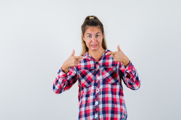 Photo gratuite portrait de jeune femme se montrant en chemise à carreaux et à la vue de face perplexe