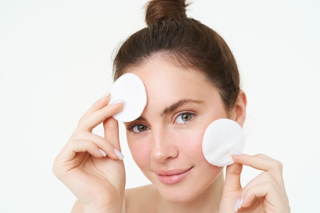 Photo gratuite portrait d'une jeune femme se nettoyant le visage, enlevant son maquillage et se lavant le visage avec des soins de la peau