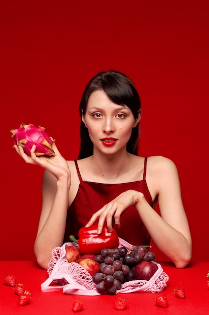 Portrait de jeune femme avec sélection de fruits et légumes rouges dans un sac en filet