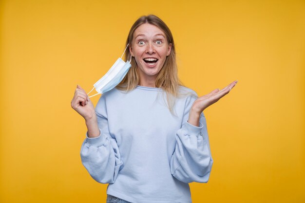 Portrait d'une jeune femme semblant excitée en enlevant son masque médical