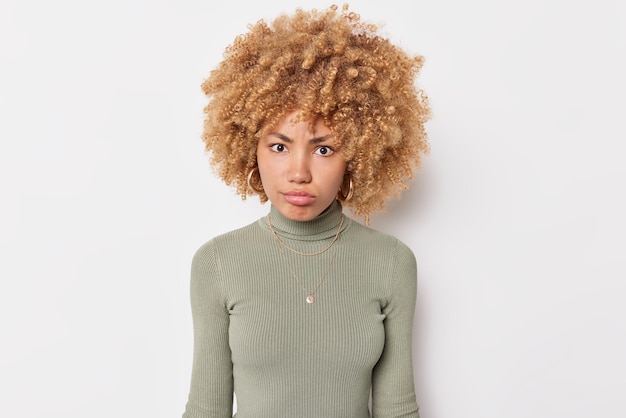 Photo gratuite portrait d'une jeune femme sérieuse a une expression de colère stricte concentrée sur la caméra vêtue de poses de cavalier décontractées sur fond blanc écoute quelqu'un analyse attentivement les informations reçues