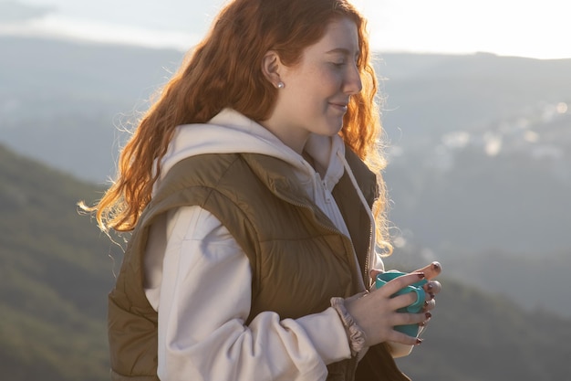 Portrait d'une jeune femme souriante buvant du thé à l'extérieur