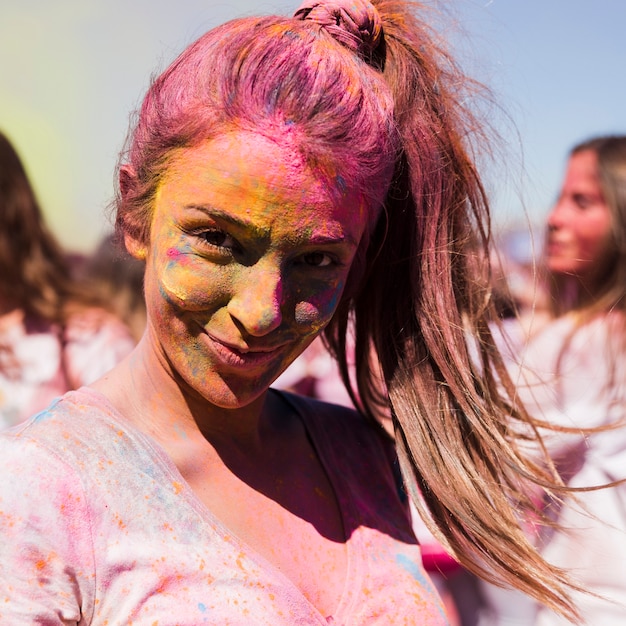 Portrait d&#39;une jeune femme souriante couverte de couleur holi