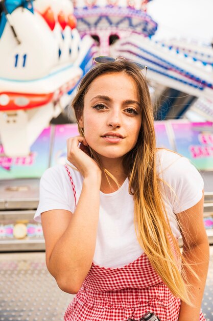 Portrait de jeune femme souriante, debout devant le parc d&#39;attractions