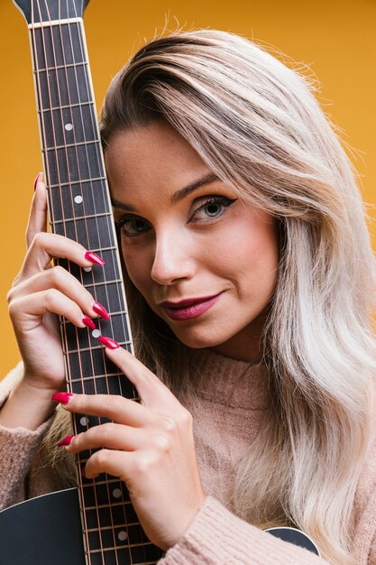 Portrait de jeune femme souriante avec guitare