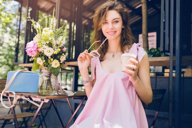 Portrait d'une jeune femme souriante heureuse et jolie assise dans un café en train de boire du café