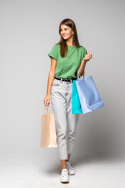 Portrait de jeune femme souriante heureuse avec des sacs à provisions sur blanc