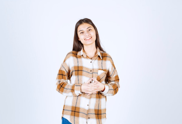 Portrait de jeune femme souriante joyeusement sur un mur blanc.