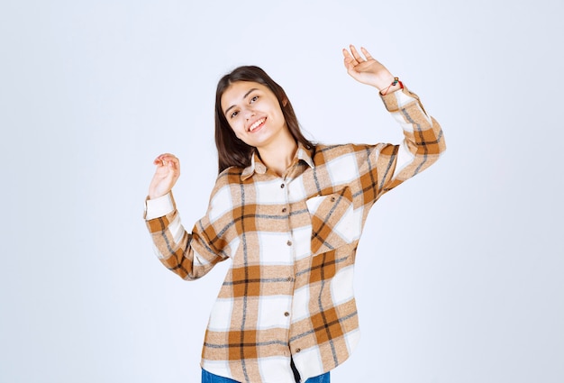 Portrait de jeune femme souriante joyeusement sur un mur blanc.