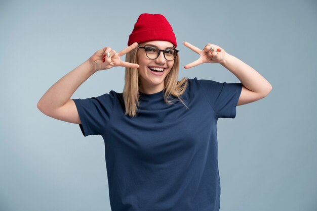 Portrait d'une jeune femme souriante et montrant le signe de la paix