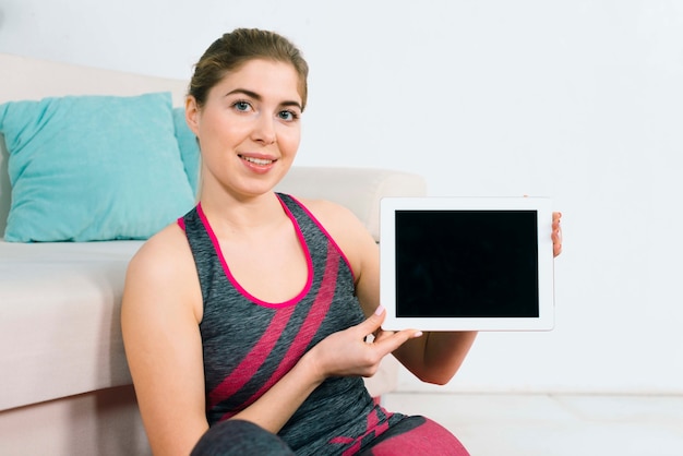Photo gratuite portrait d'une jeune femme souriante, montrant une tablette numérique vierge