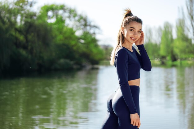 Portrait d'une jeune femme souriante portant des vêtements de sport dans le parc du matin