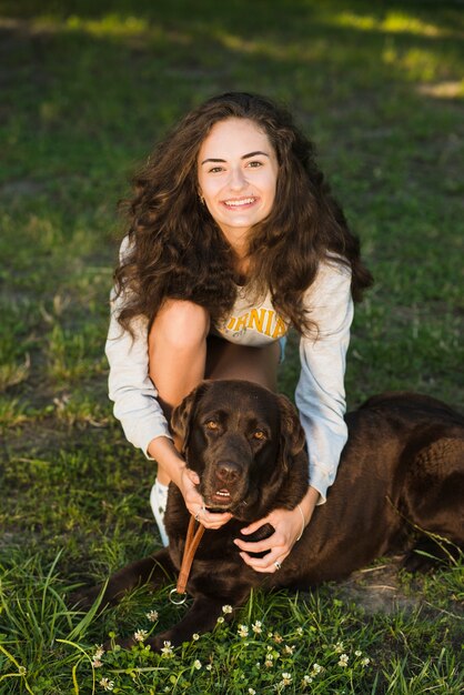 Portrait d&#39;une jeune femme souriante avec son chien dans le parc