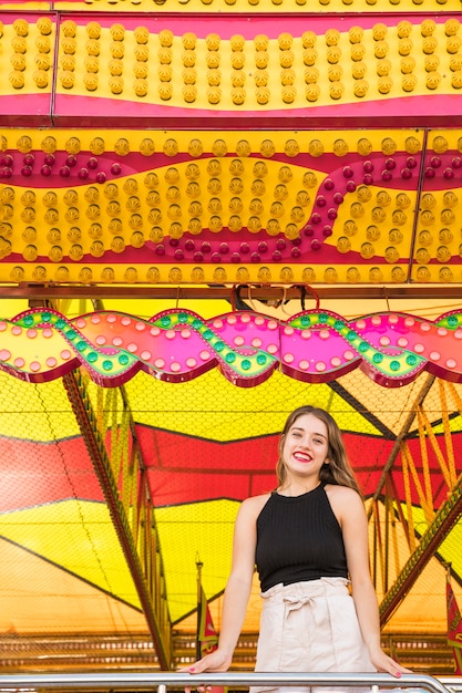 Photo gratuite portrait d'une jeune femme souriante sous la tente au parc d'attractions