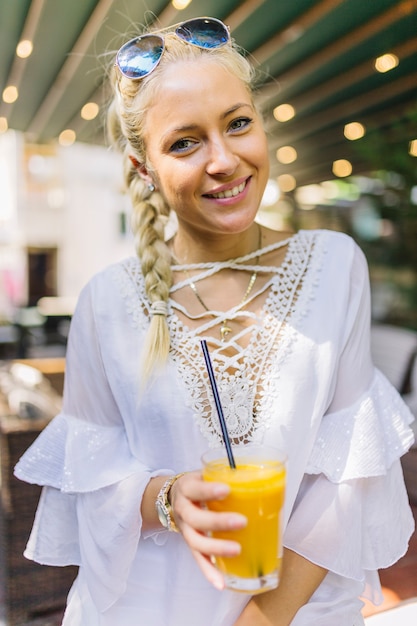 Photo gratuite portrait d'une jeune femme souriante tenant un verre de jus avec paille à boire dedans