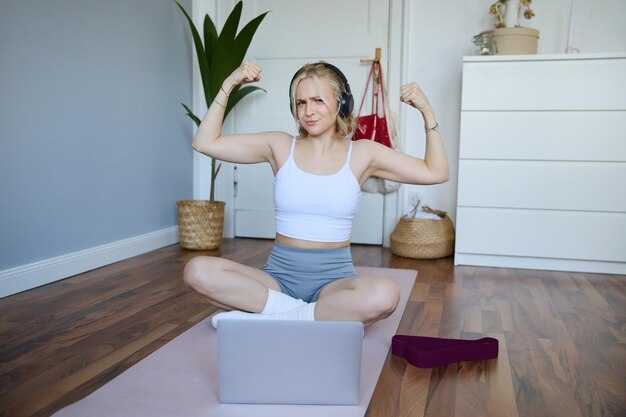 Portrait d'une jeune femme sportive suivant des instructions vidéo en ligne pendant un entraînement physique en utilisant