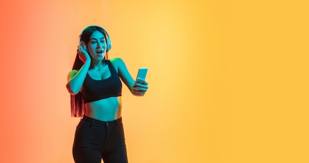 Portrait de jeune femme sur studio jaune-orange en lumière néon