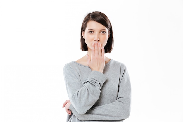 Portrait d'une jeune femme surprise couvrant sa bouche avec la main isolé sur blanc