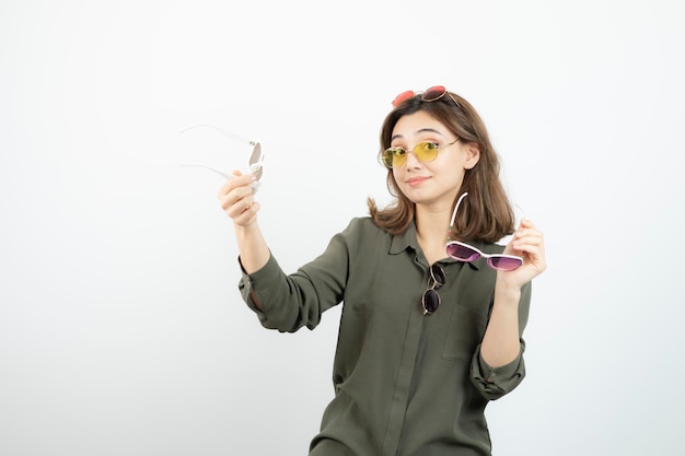 Portrait de jeune femme tenant des lunettes de soleil colorées sur blanc. Photo de haute qualité