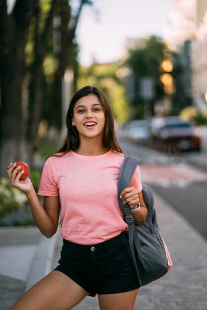 Portrait d'une jeune femme tenant une pomme contre une rue