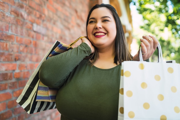 Portrait de jeune femme tenant des sacs à provisions à l'extérieur dans la rue