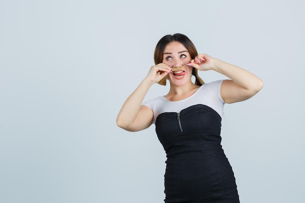 Portrait de jeune femme tenant ses cheveux comme moustache