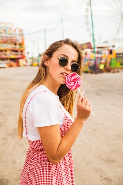 Portrait de jeune femme tenant une sucette rouge au parc d&#39;attractions