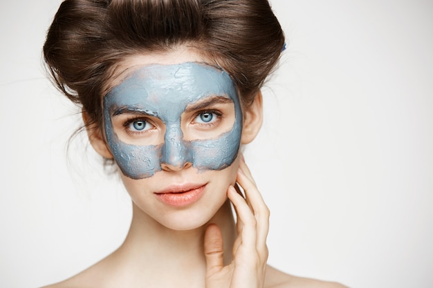 Portrait de jeune femme tendre en bigoudis et masque facial souriant. Concept de beauté et de soins de la peau.