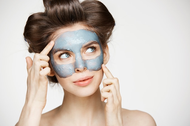 Portrait de jeune femme tendre en bigoudis et masque facial souriant. Concept de beauté et de soins de la peau.