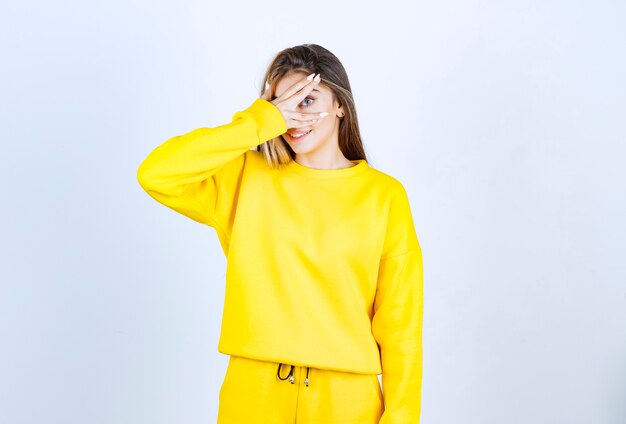 Portrait de jeune femme en tenue jaune debout et couvrant ses yeux